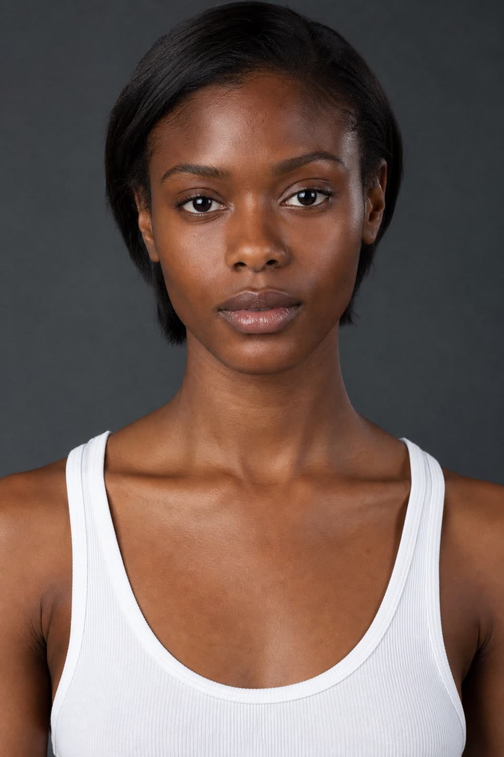 Comp card close-up, plain grey studio backdrop, white tank top
